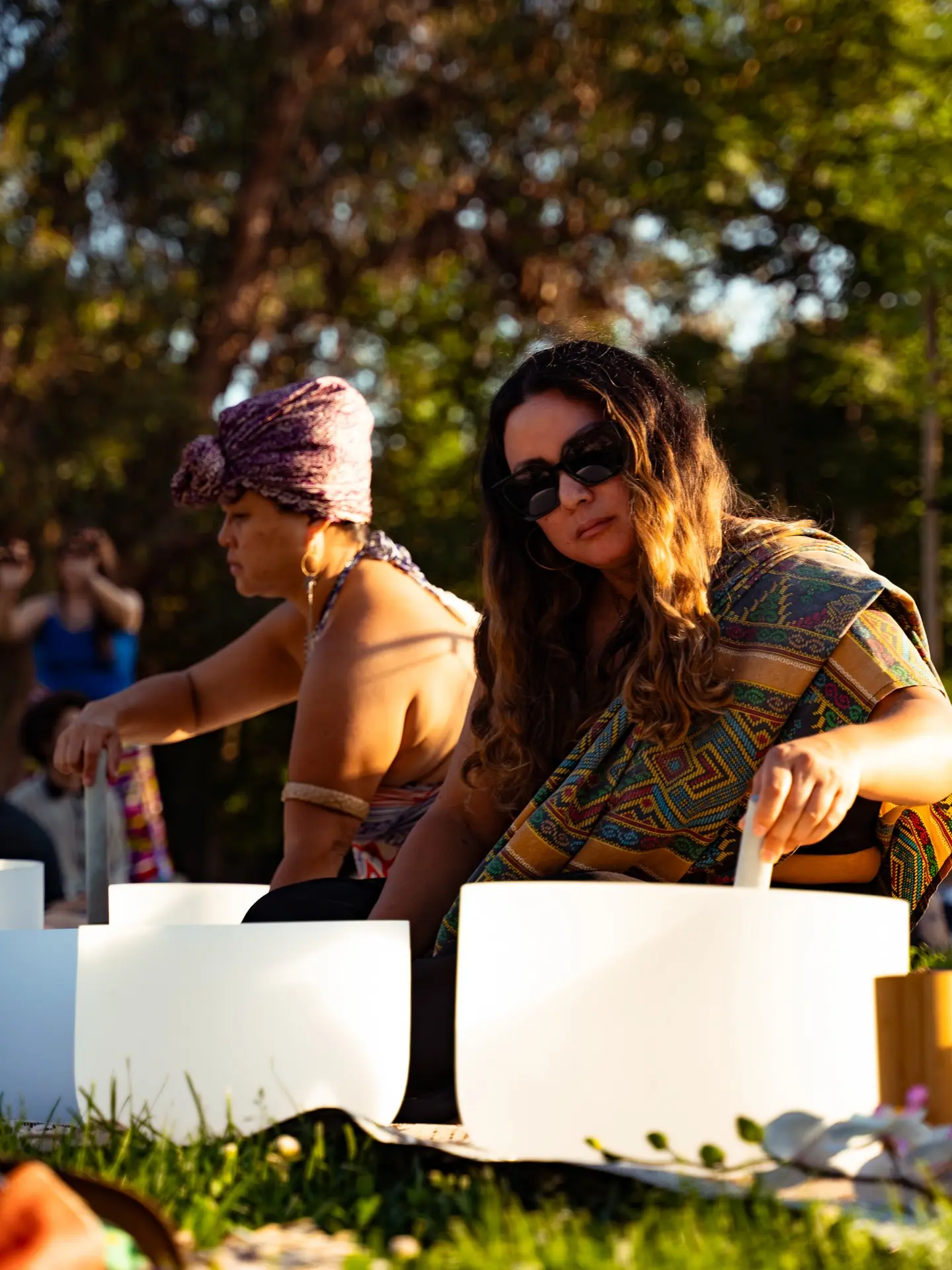 Two facilitators playing crystal singing bowls outdoors